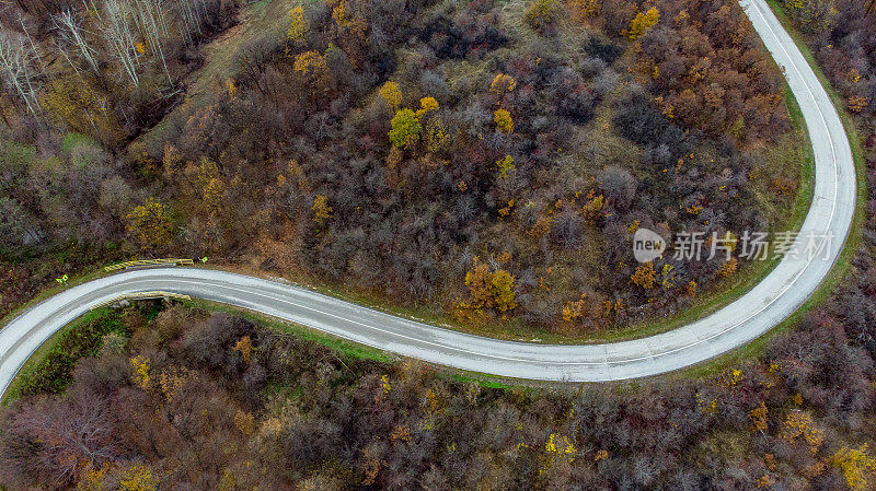 Crni Vrh -飞过空旷的秋天道路，明亮的树木在绿色，橙色和红色的色调-俯视图在塞尔维亚东部明亮的秋天颜色的森林- 4K无人机拍摄